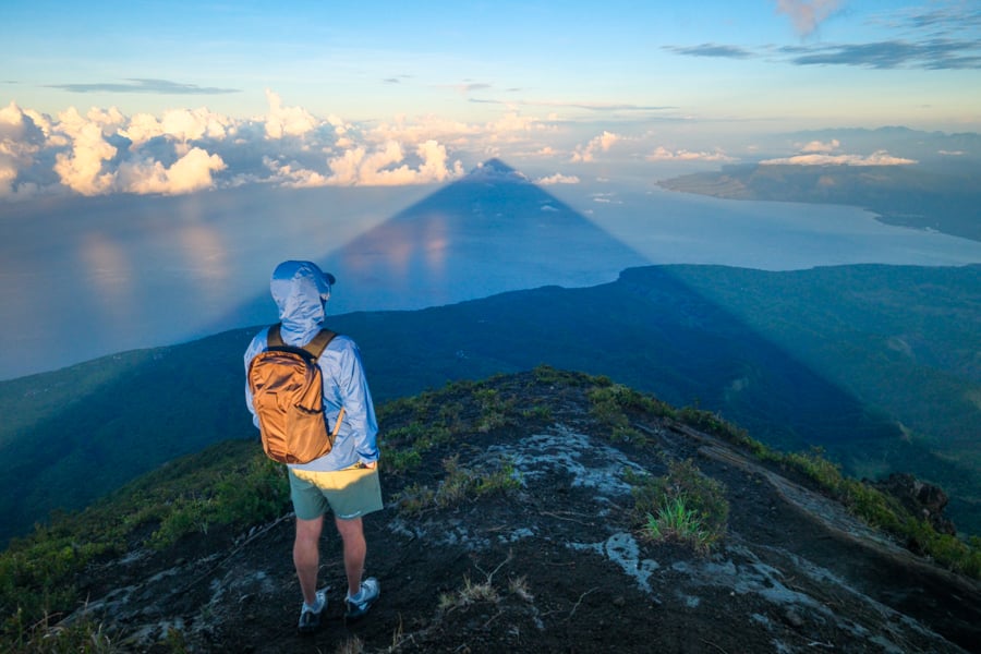 Hiker looking at the pyramid shadow on Mount Inerie volcano in Flores Indonesia