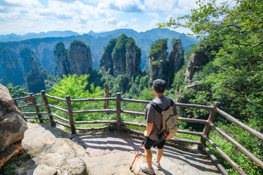 Hiker behind a fence staring at stone mountains