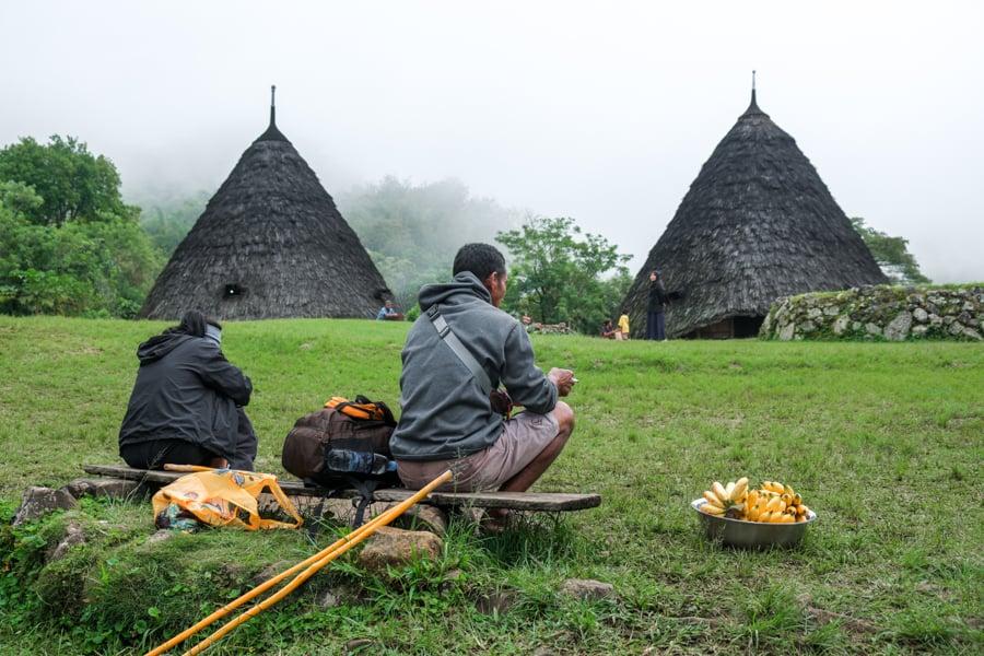 Hikers sitting on a bench at Wae Rebo village
