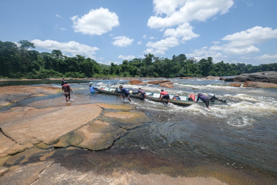 Dragging a canoe over the river rapids