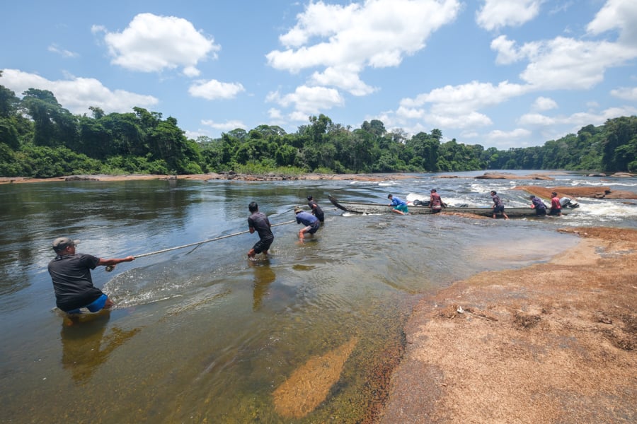 Dragging a canoe over the river rapids