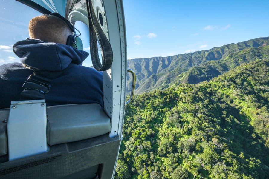 Helicopter with the door open over green mountains